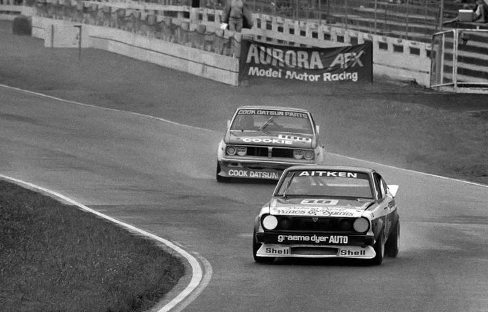 Grant Aitken's #10 ahead of Reg Cook's Datsun past an Aurora AFX banner