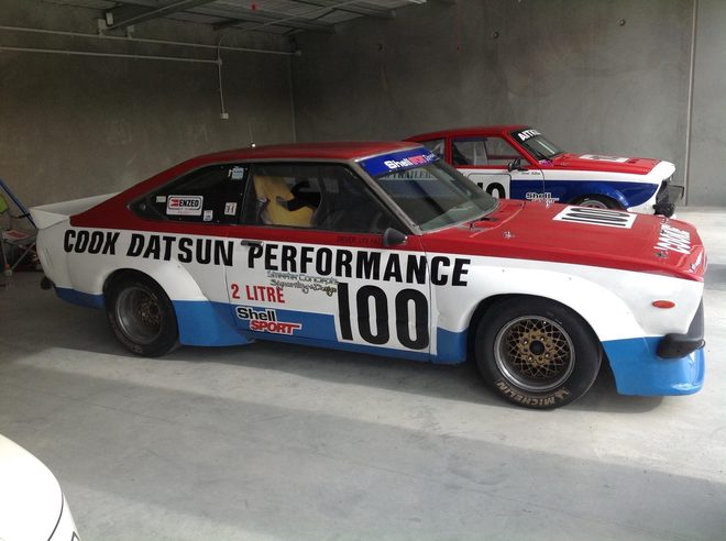 The ex-Reg Cook Datsun #100 in a garage, with Grant Aitken's Datsun #10 behind