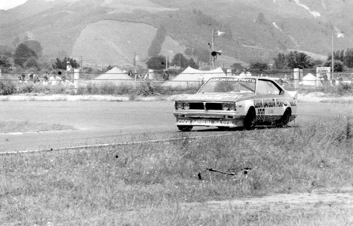 The Cook Datsun on a circuit with hills and tents behind