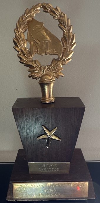 Lyn Hatton's trophy: gold wreath and racing car on a timber base with a gold star, plates reading 1975-76 L. Hatton and N.Z. National Gold Star Hill Climb Champion